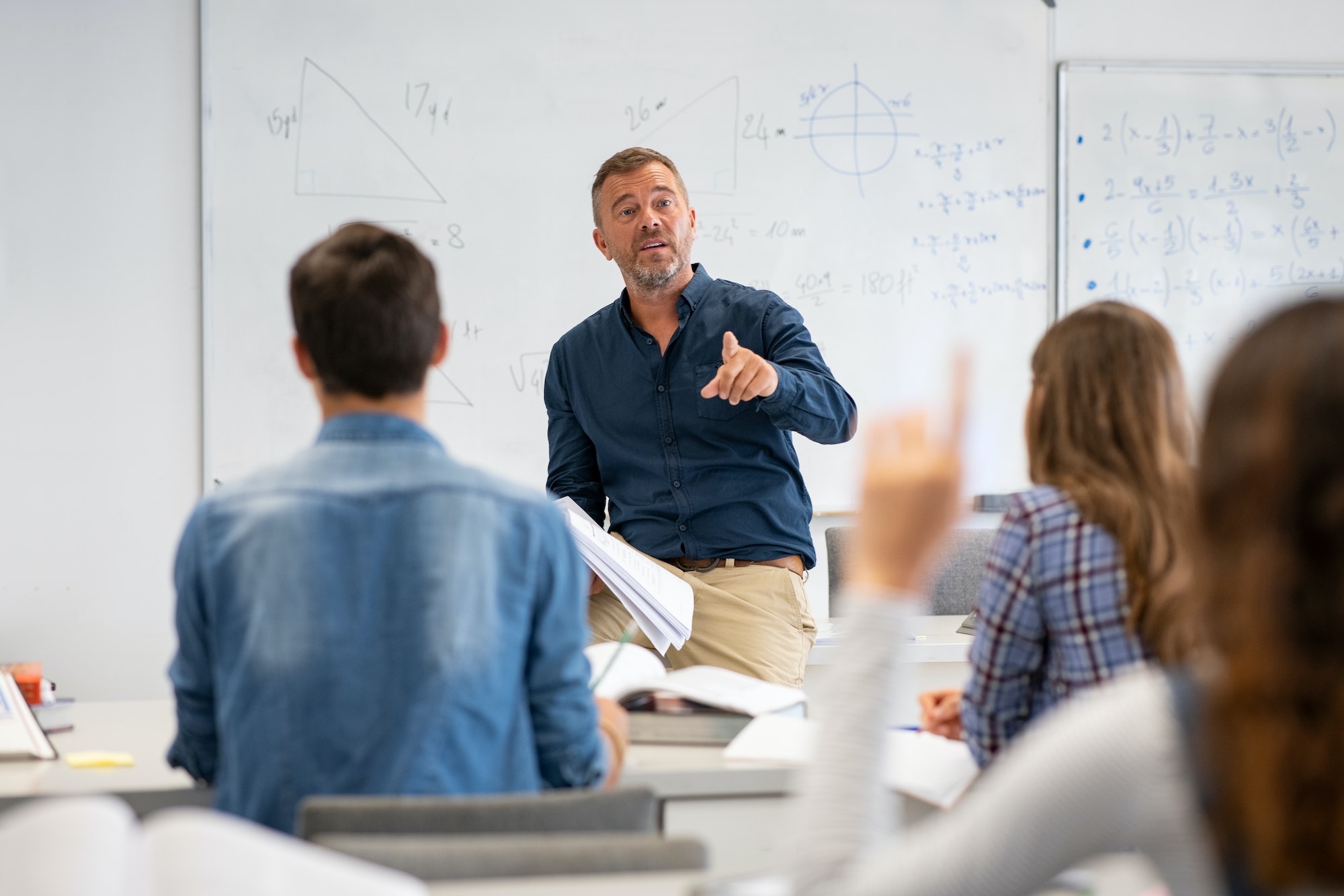 Student raising hand in classroom at the high school